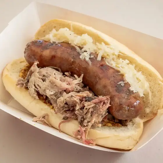 The Braterosa, a smoked bratwurst on a bun piled with pulled pork, sauerkraut and brown mustard in a paper boat