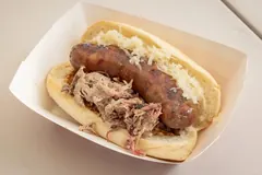 The Braterosa, a smoked bratwurst on a bun piled with pulled pork, sauerkraut and brown mustard in a paper boat